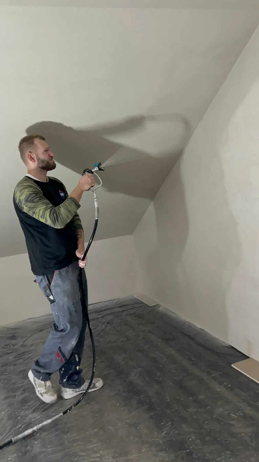 Nakładanie materiału natryskiem na skos poddasza w domu jednorodzinnym